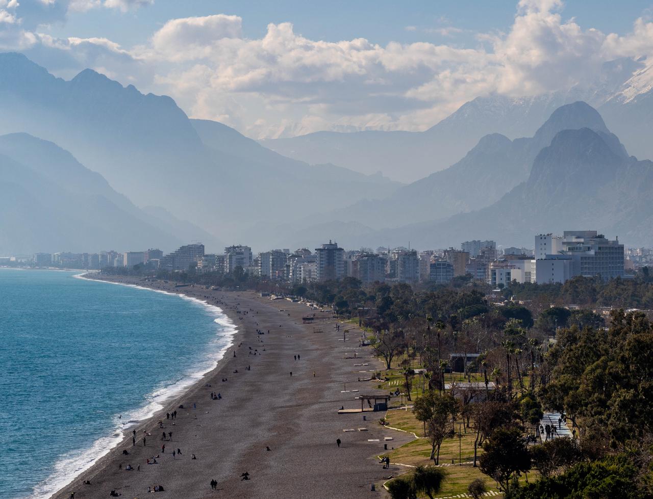 People stroll along Konyaalti Beach on a sunny winter day in Antalya, Türkiye. (Adobe Stock Photo)