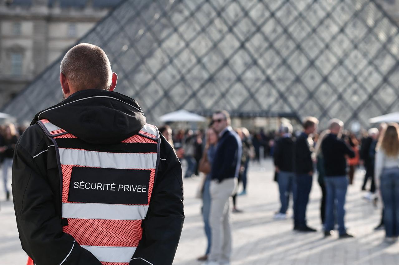 A security guard stands in front of the Pyramide du Louvre, designed by Chinese-U.S. architect Ieoh Ming Pei, with the Louvre Museum in the background in Paris on October 22, 2025. (AFP Photo)