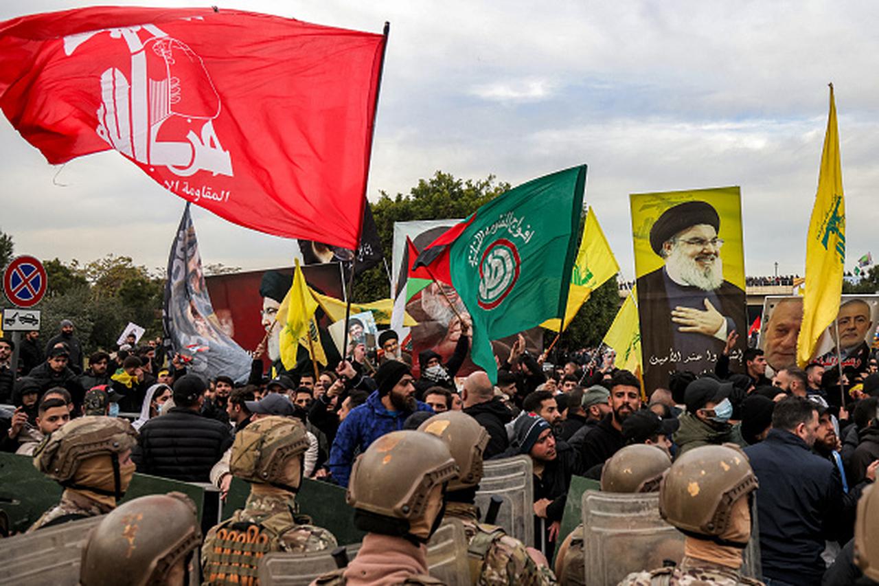 Protesters wave flags of the Lebanese Shiite movements Hezbollah and Amal with a portrait of slain Hezbollah leader Hassan Nasrallah before Lebanese Army soldiers during a Hezbollah-organised rally to block the road to Beirut International Airport, in Beirut, Lebanon, on Feb. 15, 2025. (AFP Photo)