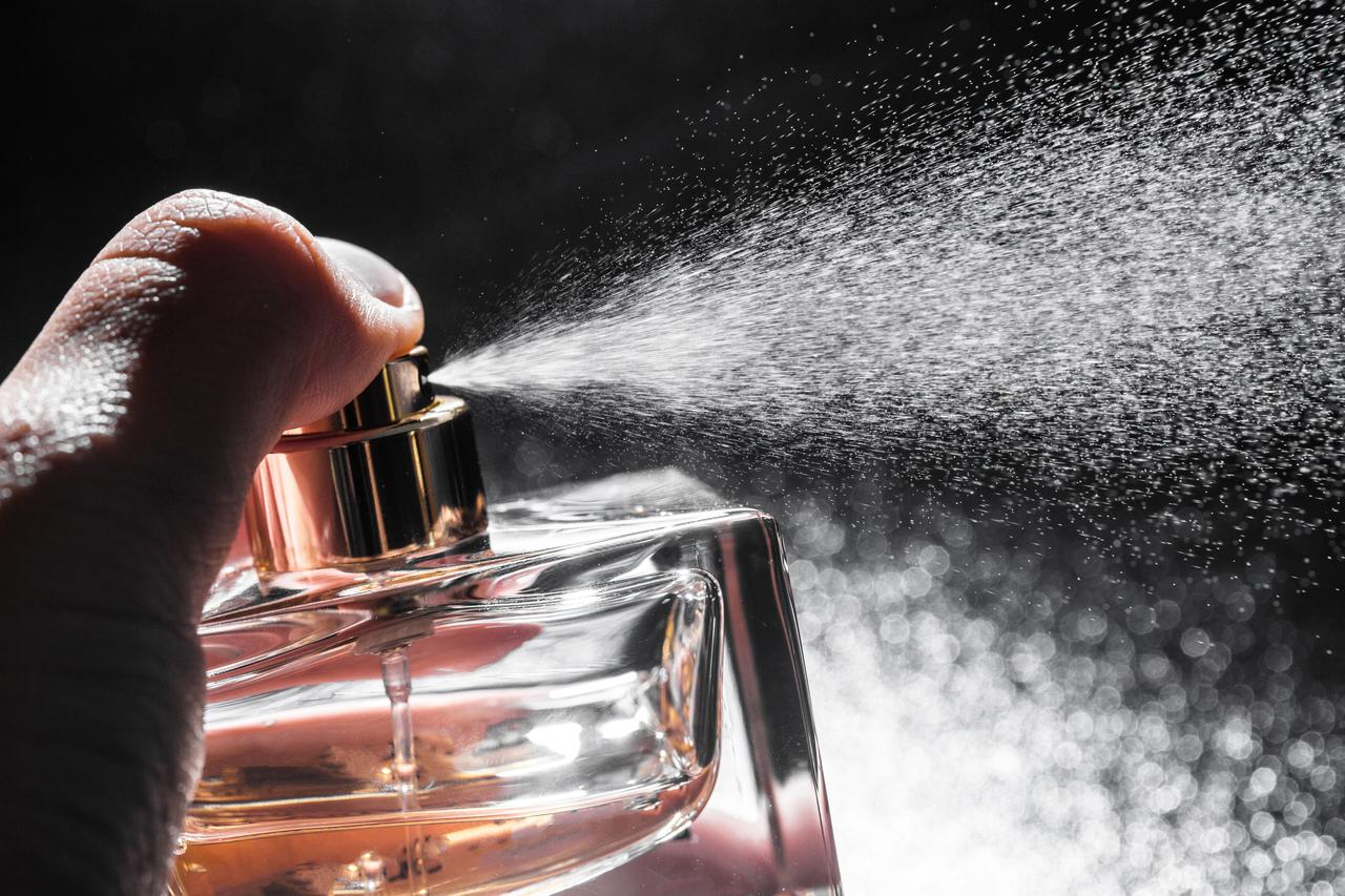 Close-up of perfume being sprayed on a dark background. (Adobe Stock Photo)
