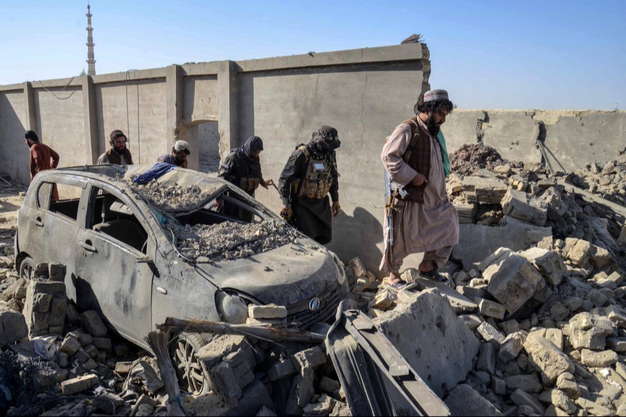Taliban security personnel walk past a damaged car in the Spin Boldak district of Kandahar province, October 16, 2025. (AFP Photo)
