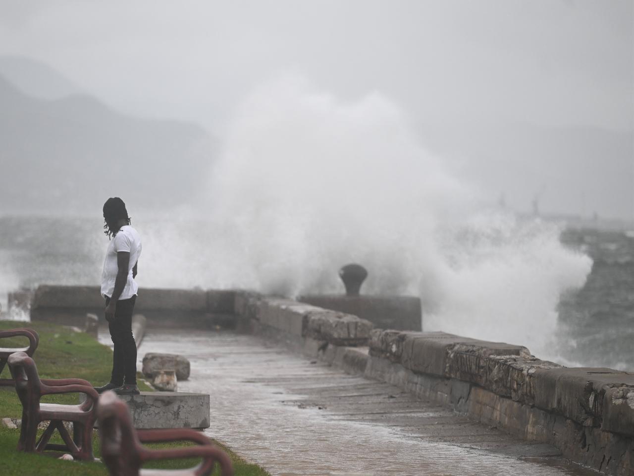 A man stands as waves crash against the walls at Kingston Waterfront, October 27, 2025. (AFP Photo)