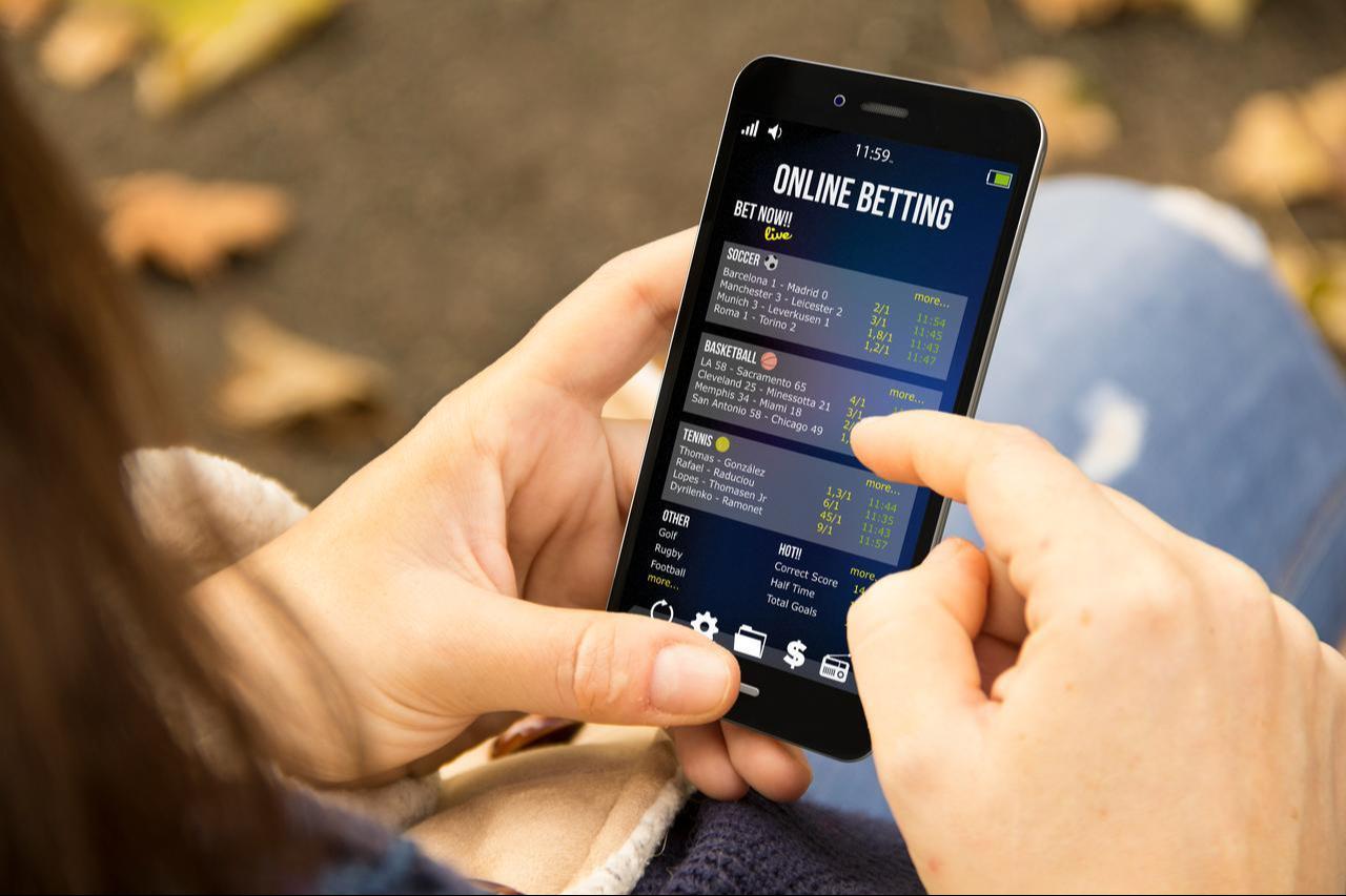 A young woman betting online at the park. (Adobe Stock Photo)