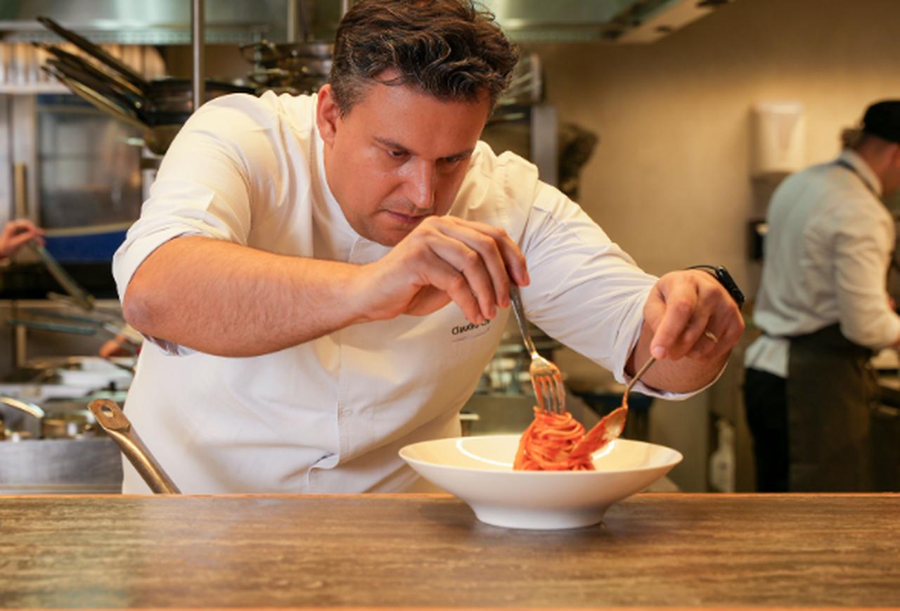 Chef Claudio Chinali meticulously plates a pasta dish in a fine dining kitchen. (Adobe Stock Photo)