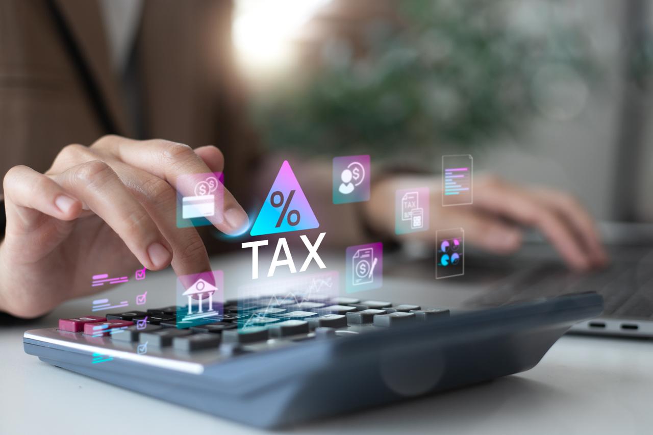 A person uses a calculator with digital tax and finance icons illustrating e-invoicing and real-time auditing concepts. (Adobe Stock Photo)