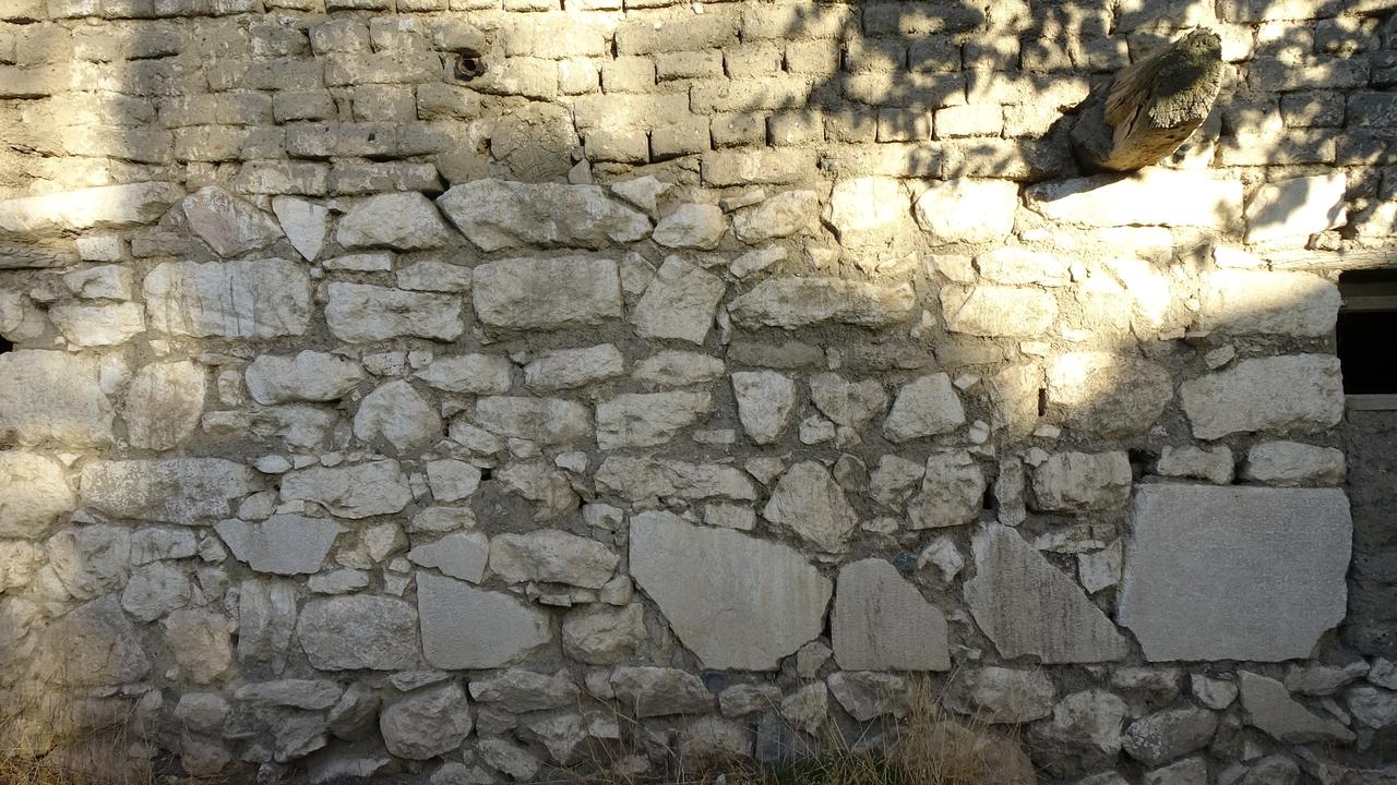 The lower section of the ruined house’s wall, constructed with large inscribed stones brought from the nearby ancient city of Takina, Burdur, Türkiye, Oct. 28, 2025. (IHA Photo)