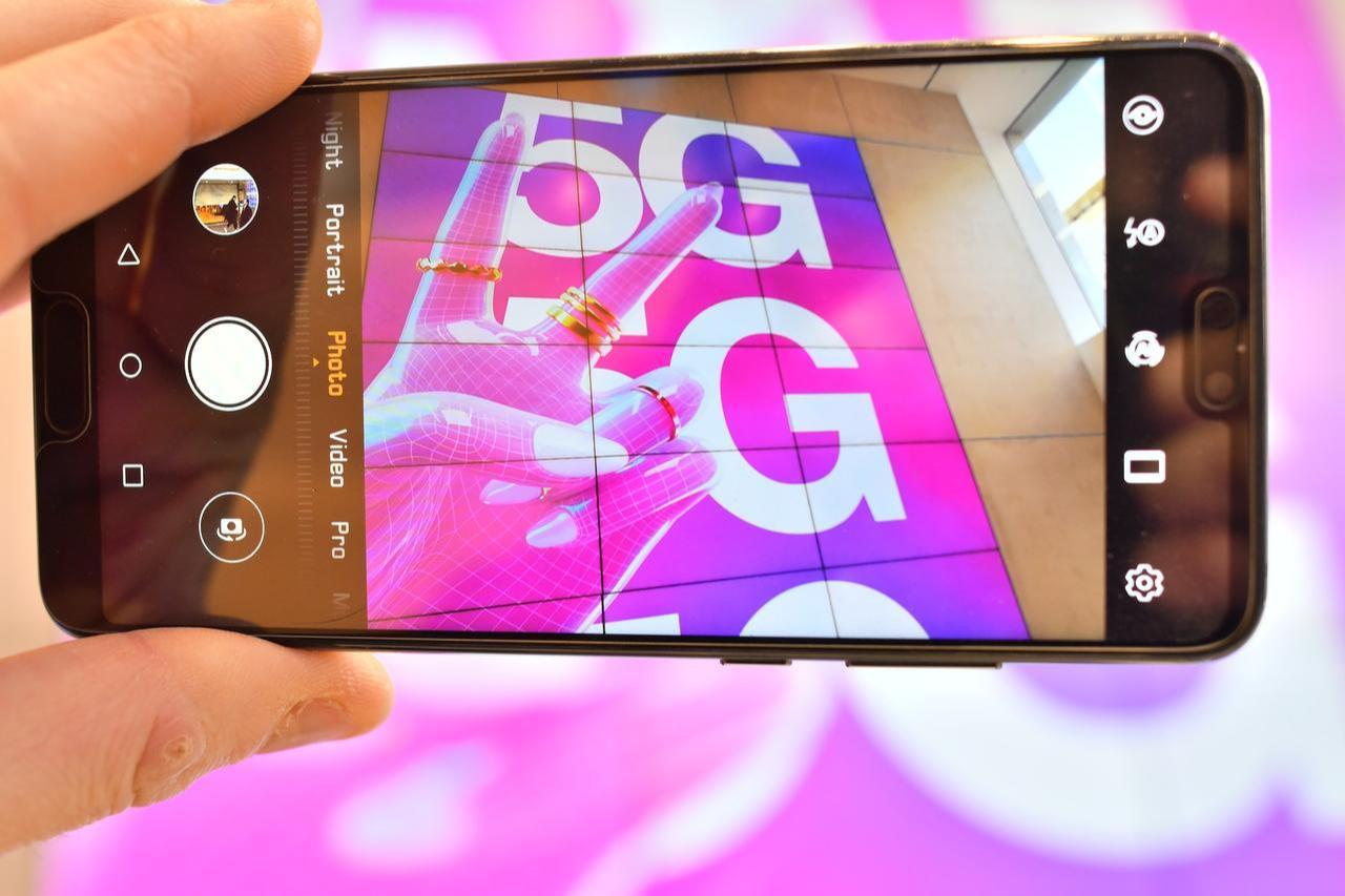 A person poses holding a mobile telephone the camera showing a sign advertising 5G mobile telecommunication in a shop in London on January 28, 2020. (AFP Photo)