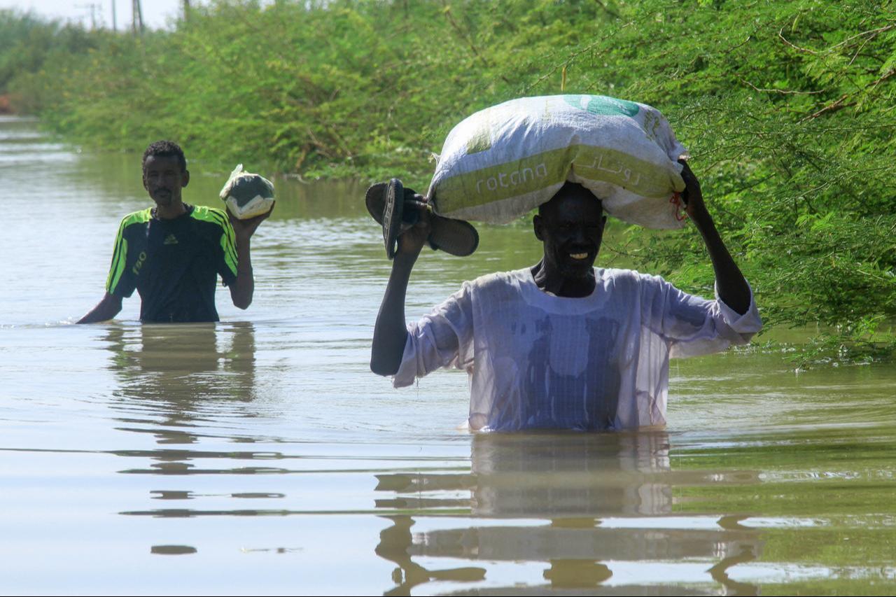 Residents wade in water as they salvage belongings due to the flooding of the Nile River in the Sudanese village of Wad Ramli, north of Khartoum, Sudan, Oct. 1, 2025. (AFP Photo )
