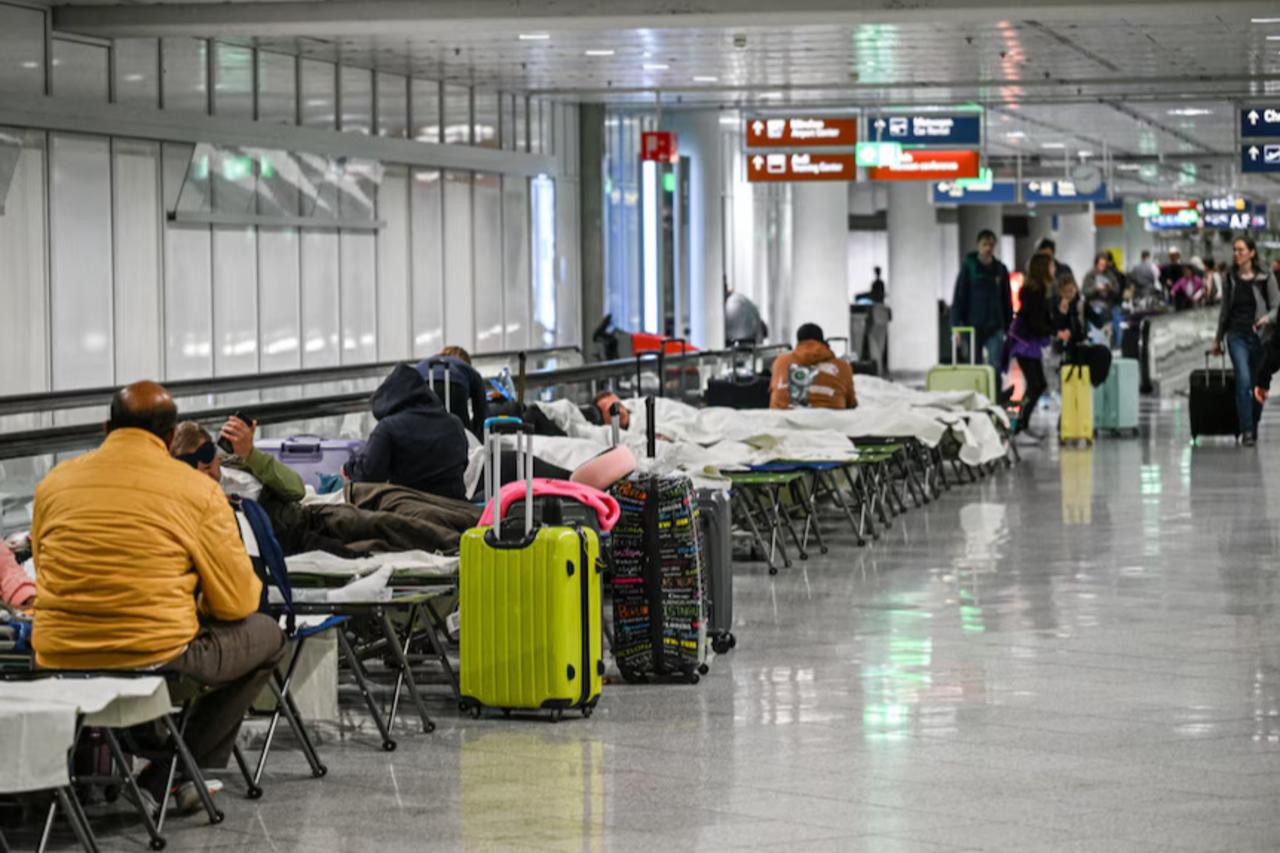 People wait on cots after drone sightings and flight cancellations at Munich Airport, Bavaria, Munich on Oct. 3, 2025. (AFP Photo)
