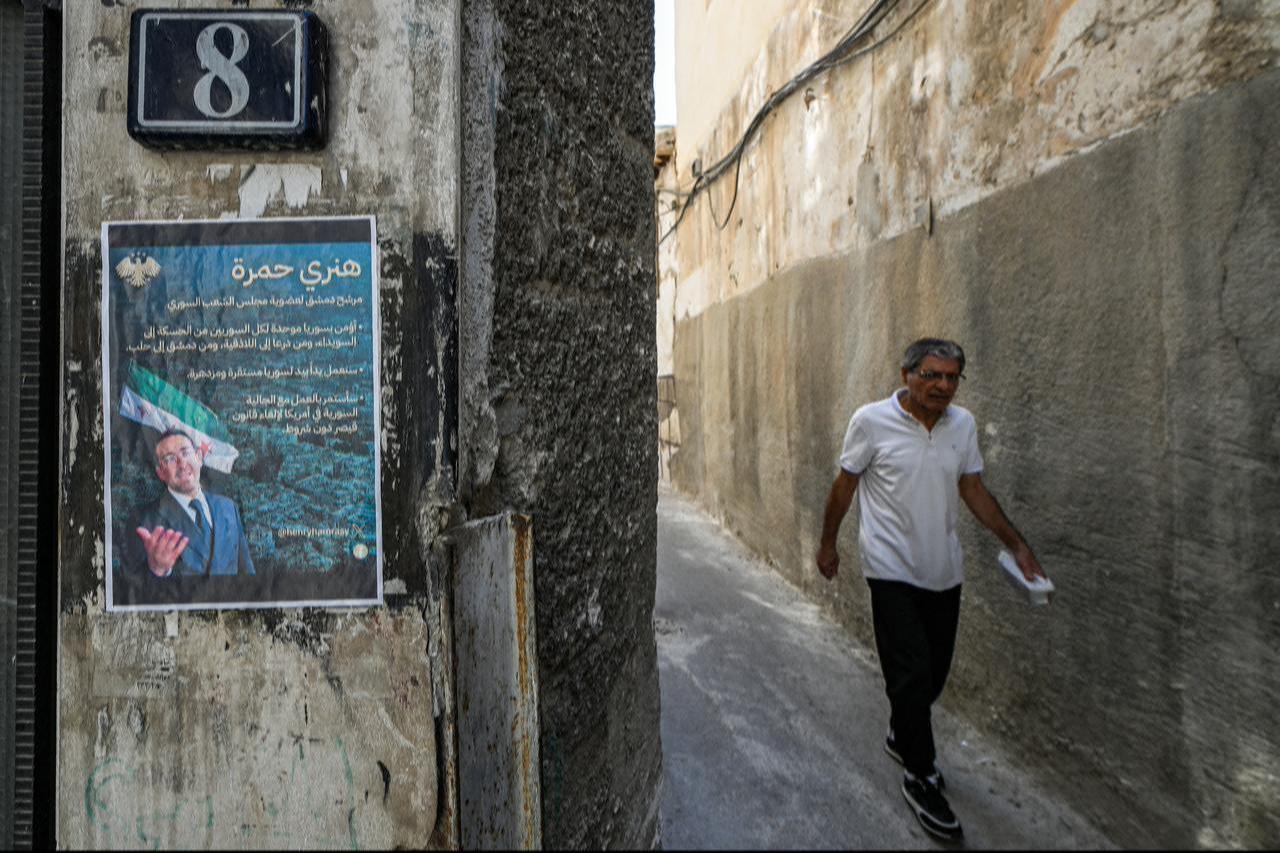 Poster od  Henry Hamra, a Syrian-American parliamentary candidate who is the first Jewish representative in the Syrian parliament since the late 1940s, displayed on a wall along an alley in the Jewish quarter of the old city of Damascus on October 3, 2025 . ( AFP Photo )