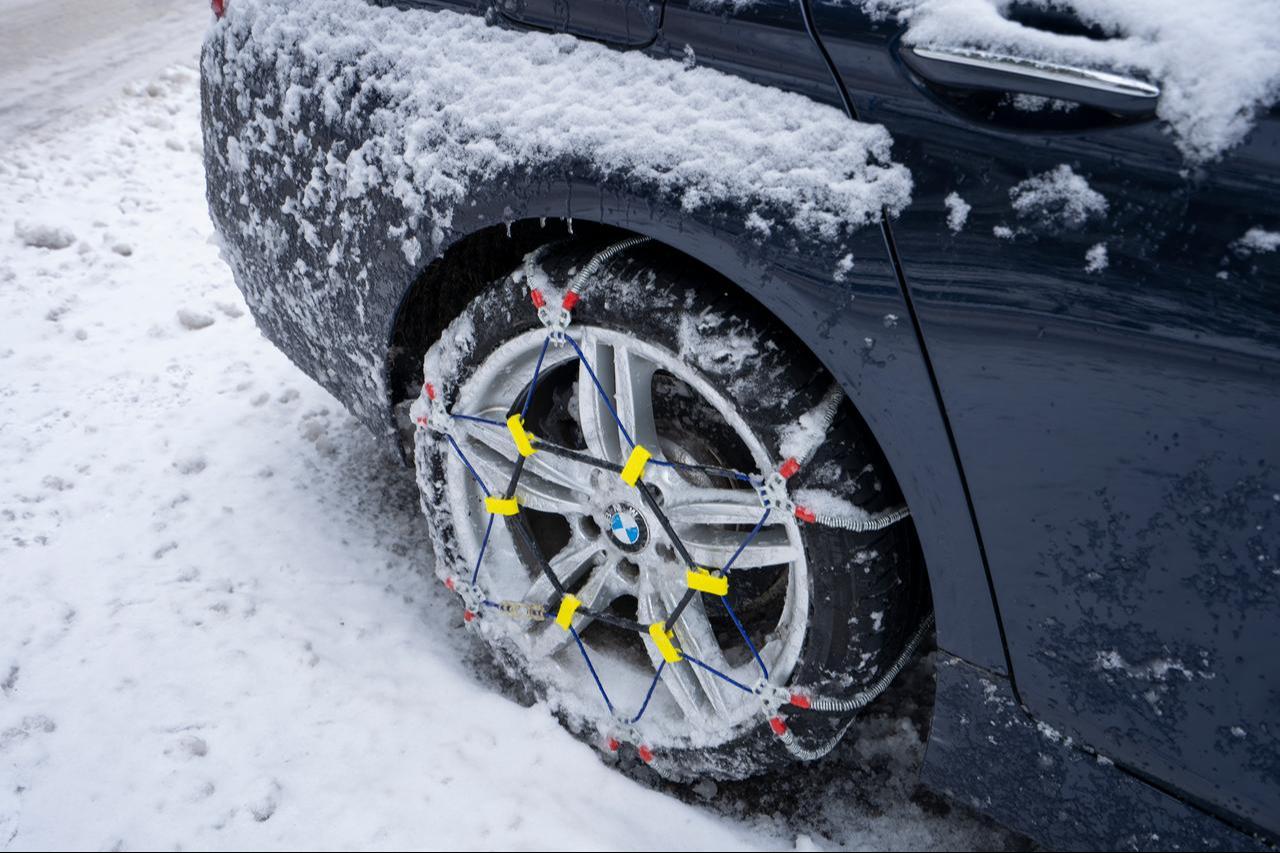 Close-up of the snow chains on the rear wheel of a BMW 535i sedan abandoned after skidding and hitting the roadside guardrail in Portland, US, Feb 23, 2023. (Adobe Stock Photo)