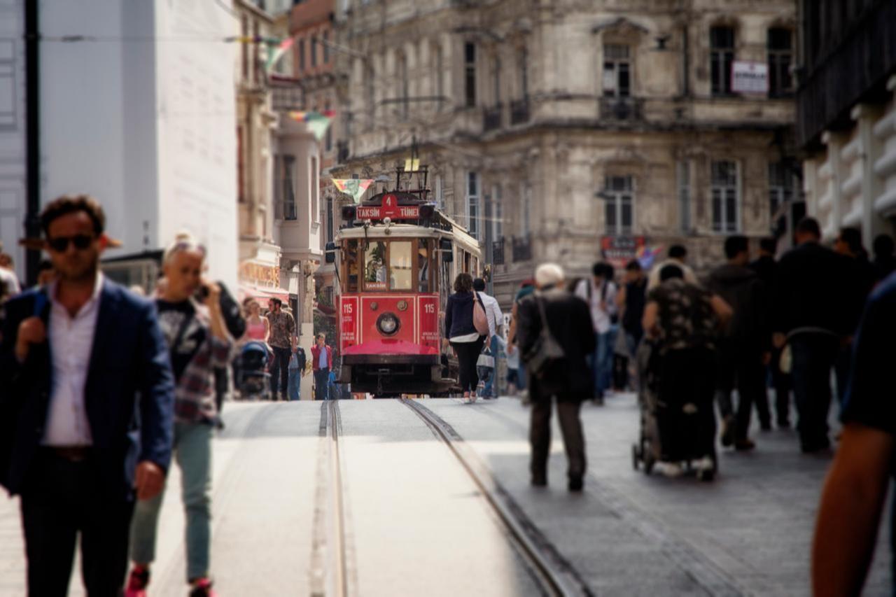 The historic red tram travels through Taksim as people walk along Istiklal Avenue in Istanbul, Türkiye, May 2, 2018. (Adobe Stock Photo)