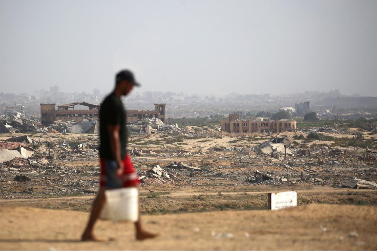 A Palestinian man transports buckets of water next to a coastal path northwest of Nuseirat refugee camp after being displaced southward in Gaza Strip on October 4, 2025. (AFP Photo)