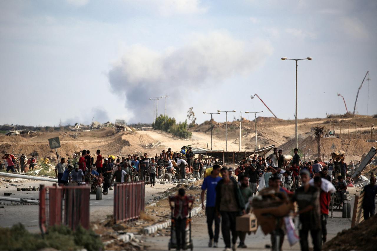 A plume of smoke rises in the background as Palestinians return from a food distribution point run by the Gaza Humanitarian Foundation (GHF), Gaza Strip, October 5, 2025. (AFP Photo)