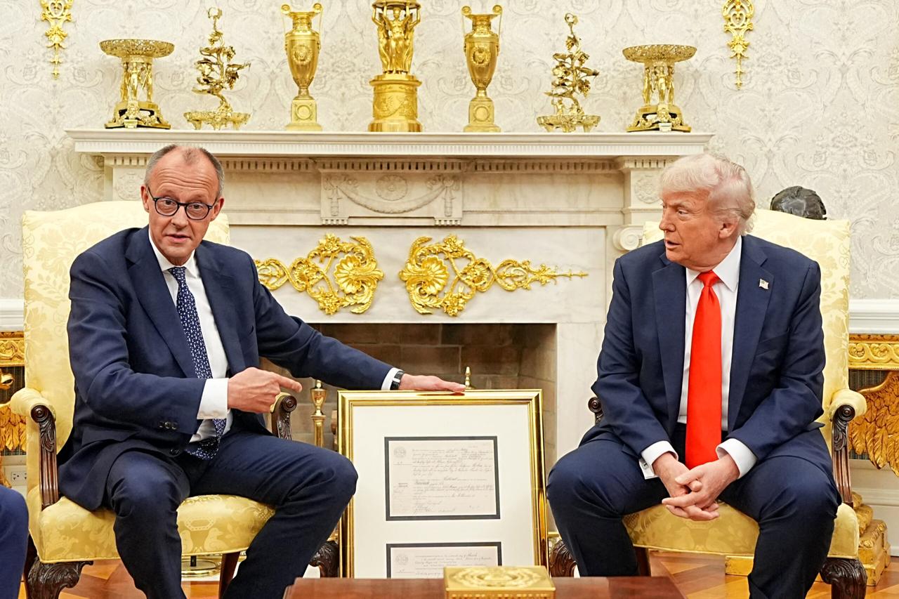 German Chancellor Friedrich Merz gives US President Donald Trump a present of a facsimile of the birth certificate of Friedrich (later Frederick) Trump, grandfather of US President Donald Trump, in the Oval Office of the White House in Washington, DC, on June 5, 2025. (AFP Photo)