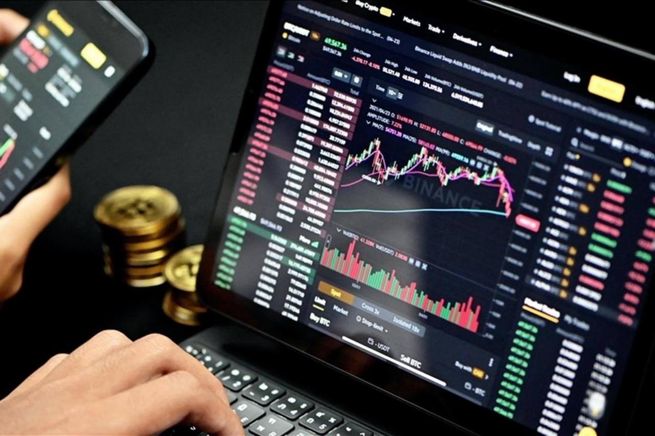 File photo shows a person trading cryptocurrency on a laptop and smartphone. (AA Photo)