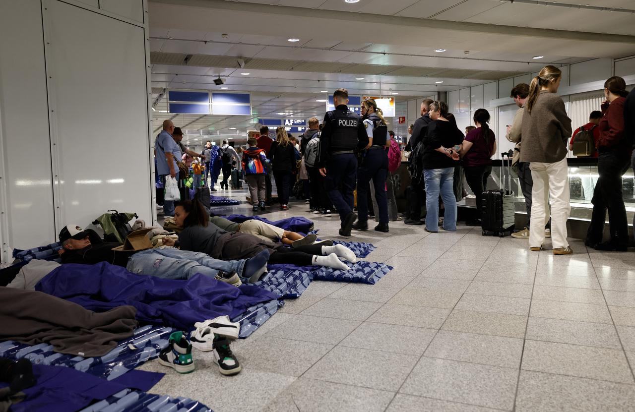 Passengers wait on the floor and in queues at Munich Airport after drone sightings forced the airport to close, canceling over 30 flights and stranding nearly 3,000 travelers, October 4, 2025. (AFP Photo)