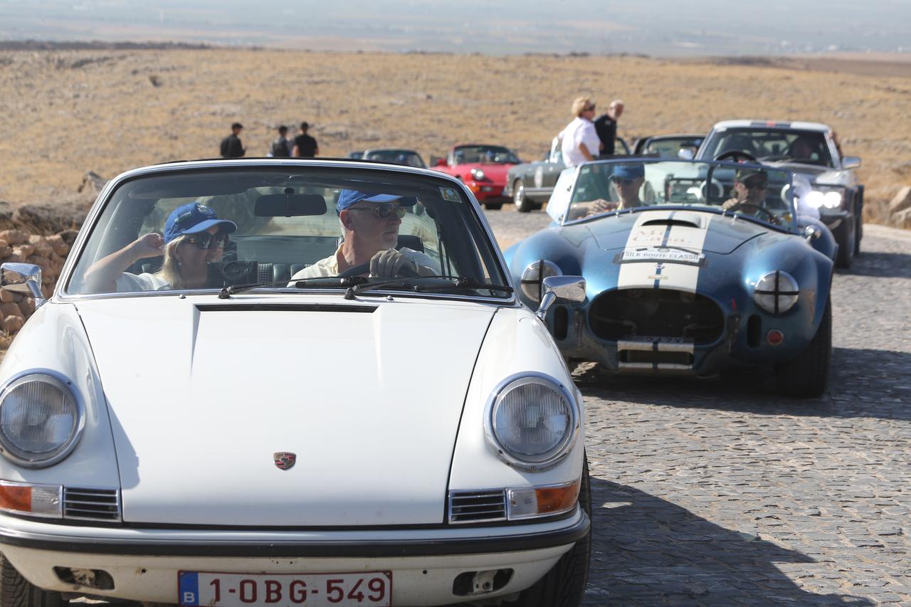 Classic car enthusiasts, who traveled from Belgium and toured two countries before arriving in Türkiye, visits Gobeklitepe, a UNESCO World Heritage site, in Sanliurfa, Türkiye, Oct. 6, 2025. (AA Photo)