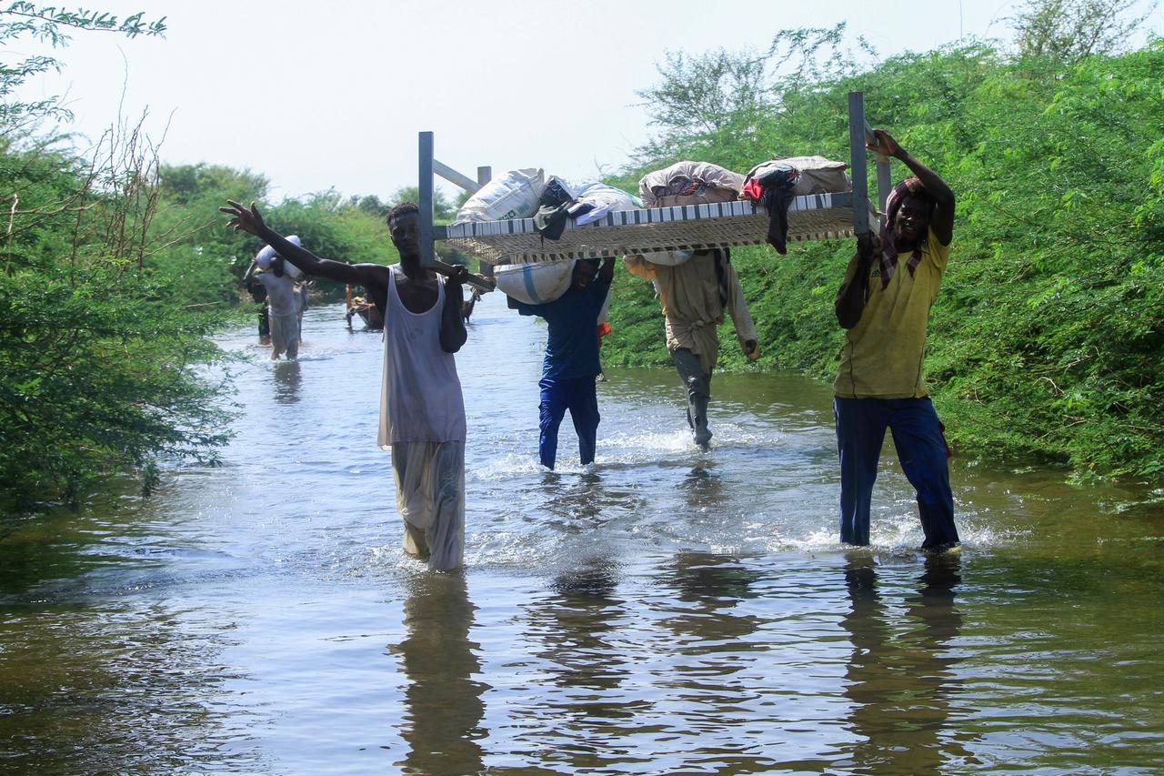Residents wade in water as they salvage belongings due to the flooding of the Nile River in the Sudanese village of Wad Ramli, north of Khartoum, Sudan, October 1, 2025. ( AFP Photo )
