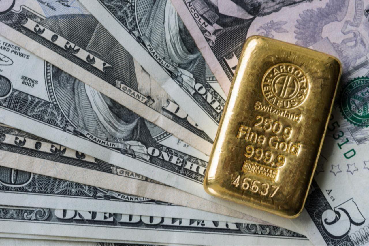A 250-gram Swiss gold bar rests on U.S. dollar banknotes. (Adobe Stock Photo)