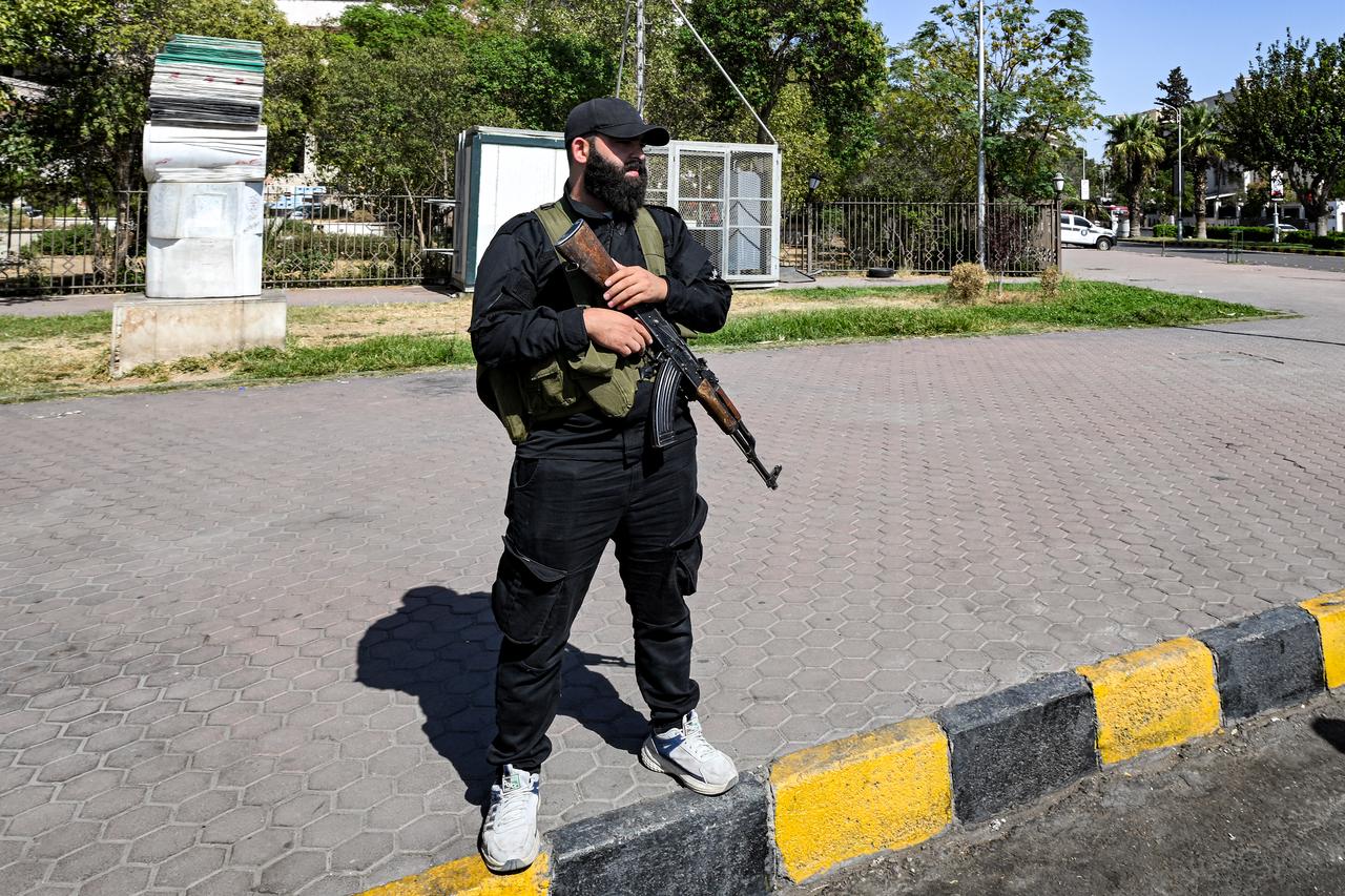 A member of Syrian security forces stands guard outside a polling station where members of Syrian local committees have been casting their votes, in Damascus, Oct. 5, 2025. (AFP Photo)