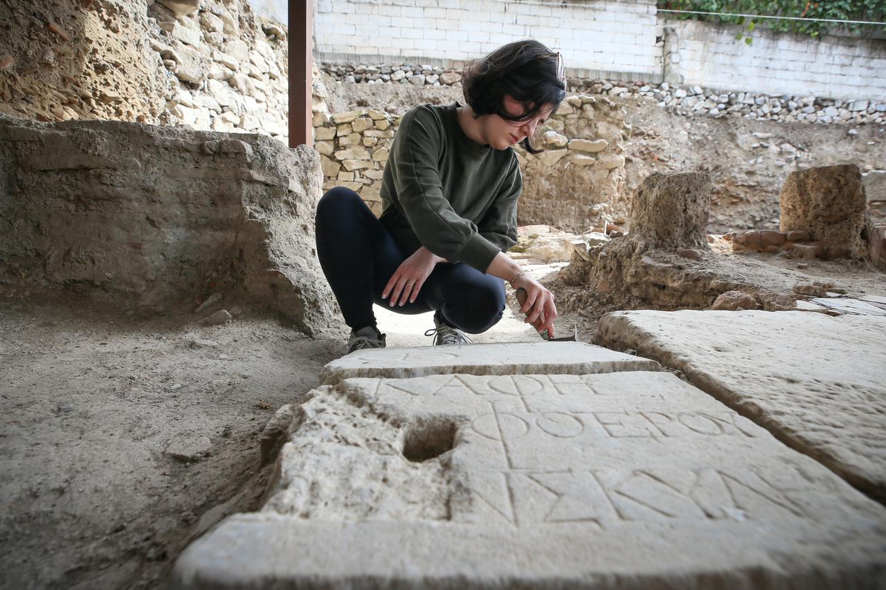 Bir arkeolog, Bursa'daki İznik Çini Fırınları'ndaki Bizans Şapeli alanında bulunan yazıtlı bir taş levhayı inceliyor, Türkiye, 7 Ekim 2025. (AA Fotoğraf)
