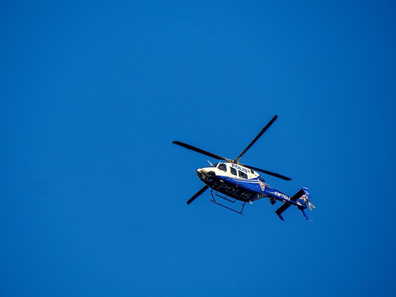 A blue and white police helicopter with its rotors in motion, flying against a clear blue sky on a patrol mission over the city of Istanbul, Türkiye. (Adobe Stock Photo)
