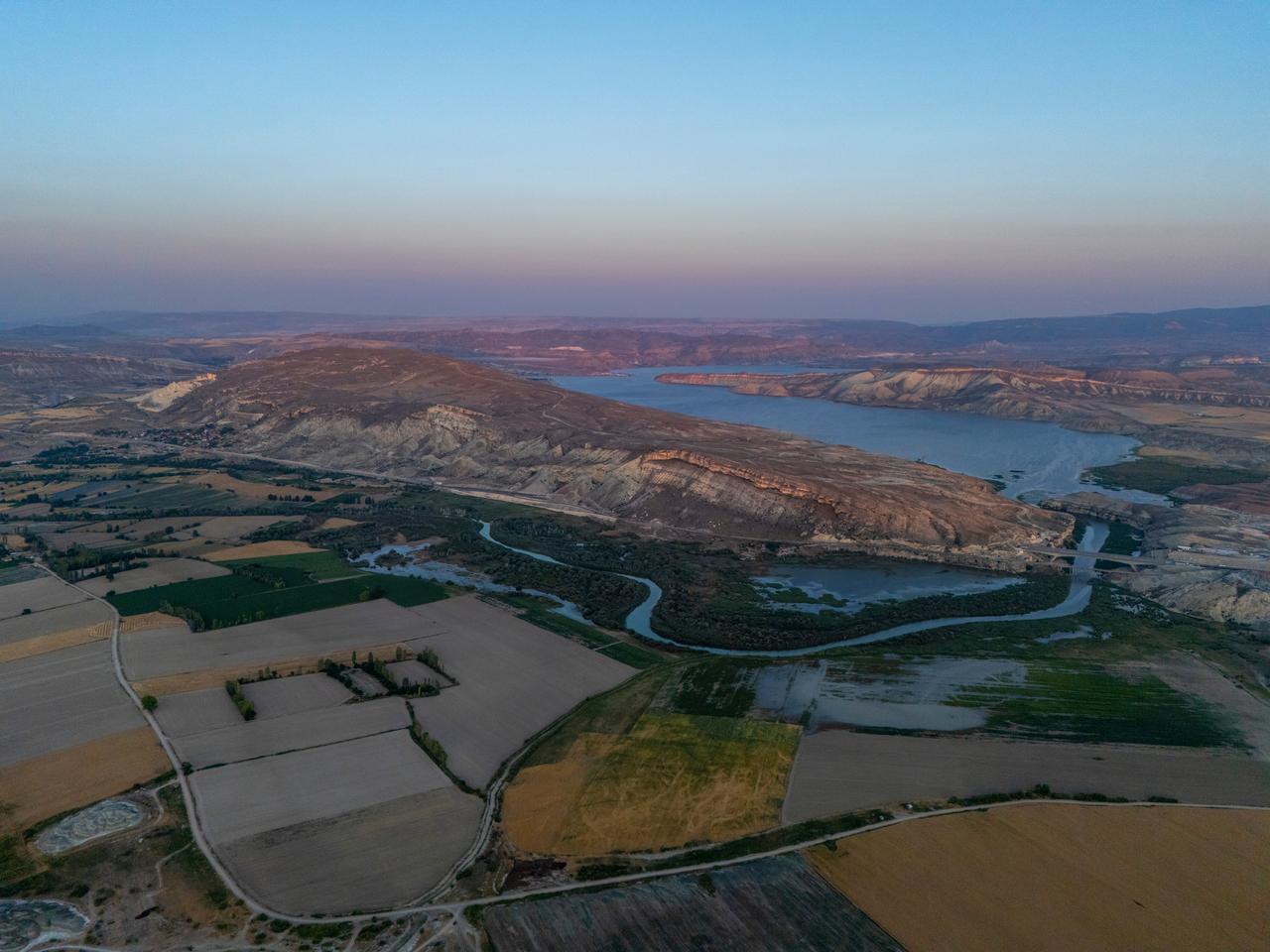Aerial view of a winding river, cultivated farmlands, and surrounding mountains in Ankara, Türkiye. (Adobe Stock Photo)