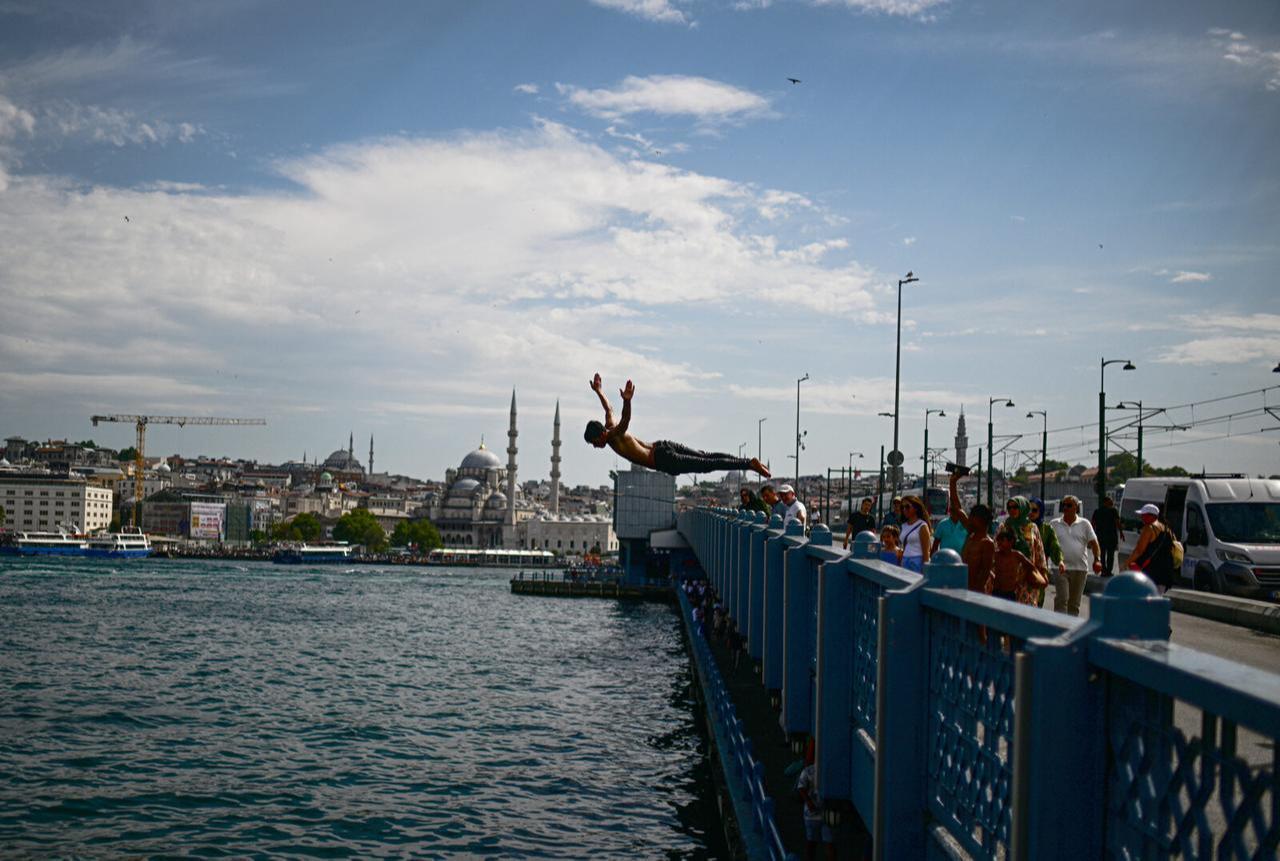 A boy jumps into the sea at the shore of Karakoy as people are overwhelmed by the hot weather and humidity and try to cool off themselves at Eminonu beach in Istanbul, Türkiye, July 16, 2024. (AA Photo)