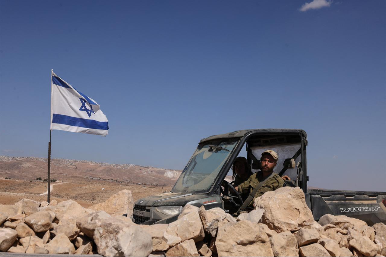 An Israeli settler using military clothes drives a vehicle in an olive field after a reported settlers attack on a village south of Yatta, in occupied West Bank, Oct. 8, 2025. (AFP Photo)