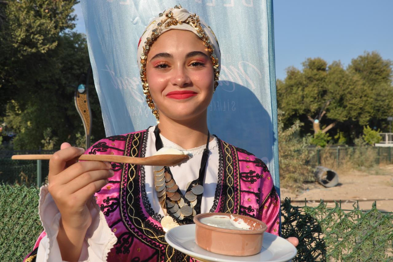 A young woman in traditional attire offers a taste of Silifke Yogurdu, Türkiye’s first EU-protected yoghurt, during a local event in Silifke, Mersin, Türkiye, Jan. 23, 2025. (IHA Photo)
