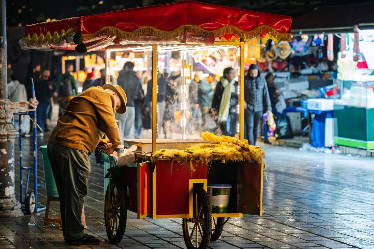 A street vendor sells roasted corn from his cart on a rainy evening in Istanbul, Türkiye. (Adobe Stock Photo)