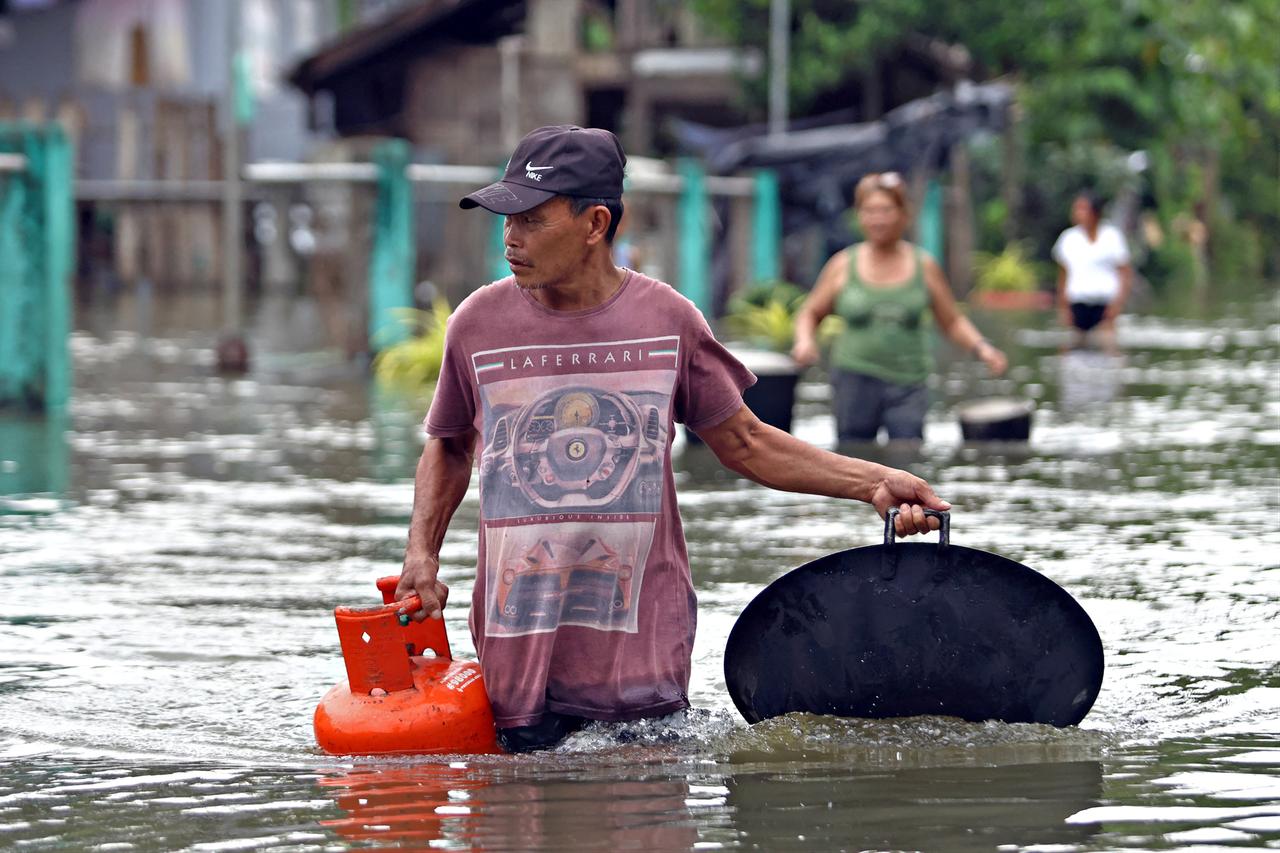 Residents are seen leaving their flooded homes in Remedios T. Romualdez on Mindanao’s southern island, as heavy rains from Typhoon Fung-wong inundate the area. Mindanao, Philippines, November 8, 2025. (AFP Photo)