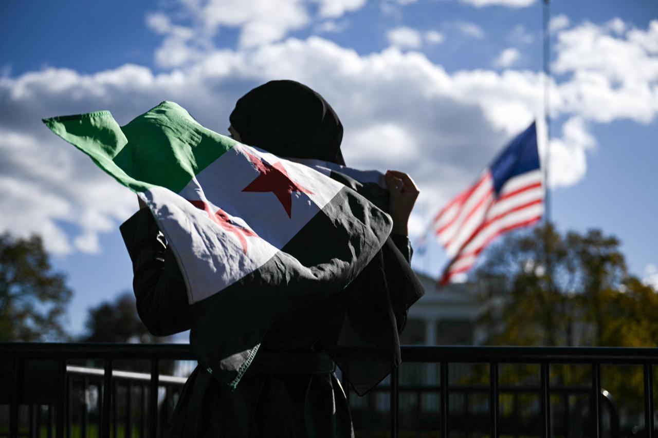 A man holds a Syrian flag across the street from the White House after Syrian President Ahmed al-Sharaa met with US President Donald Trump at White House in Washington, DC on Nov. 10, 2025. (AFP Photo)