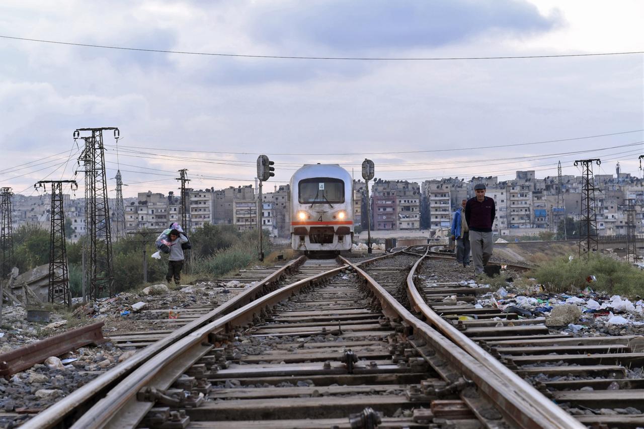 Syrians walk by the rails as a train leaves Aleppo's station on the first test ride as authorities aim to rehabilitate and reopen the line connecting the northern city to the capital Damascus, Syria on Nov. 5, 2020. (AFP Photo)