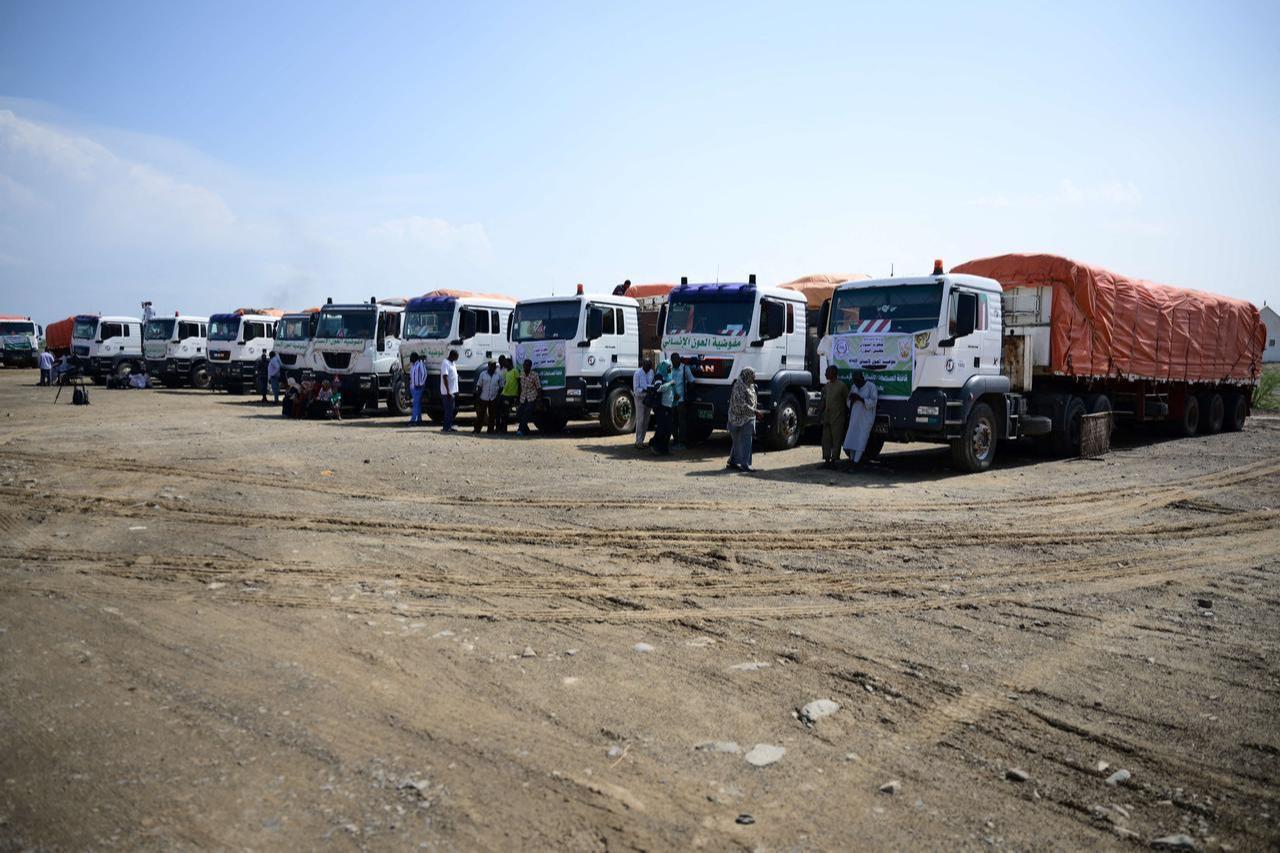 People stand near trucks loaded with aid in Port Sudan during the launch of a humanitarian aid convoy heading to the northern town of Al-Dabba, November 13, 2025. (AFP Photo)