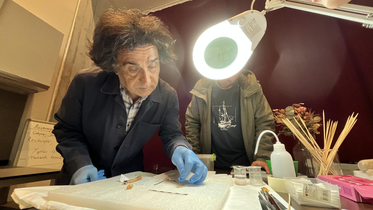 Professor Rustem Aslan examines newly unearthed Bronze Age artefacts under laboratory lighting at the Troy Museum, Canakkale, Türkiye, Nov. 17 2025. (AA Photo)