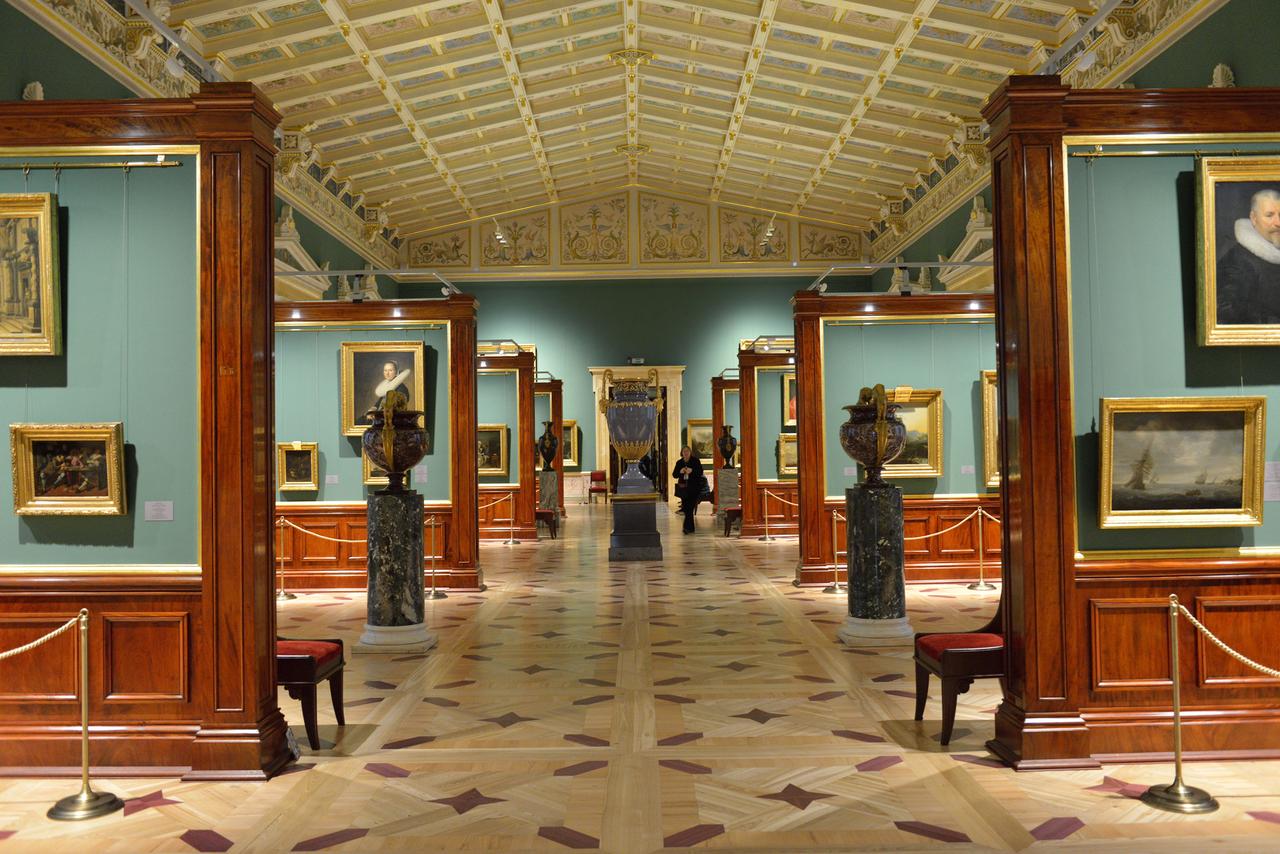 A painting gallery inside the Hermitage displays works in gilded frames, set among polished wooden columns and a coffered ceiling in one of the museums historic wings. (Adobe Stock Photo)