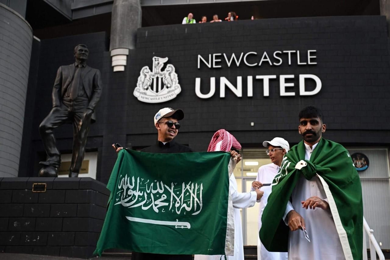 The image captures the moment Newcastle United fans, including individuals with a Saudi Arabia flag, celebrated outside St James' Park after a Saudi-led consortium completed its takeover of the club in October 2021.  (AFP Photo)