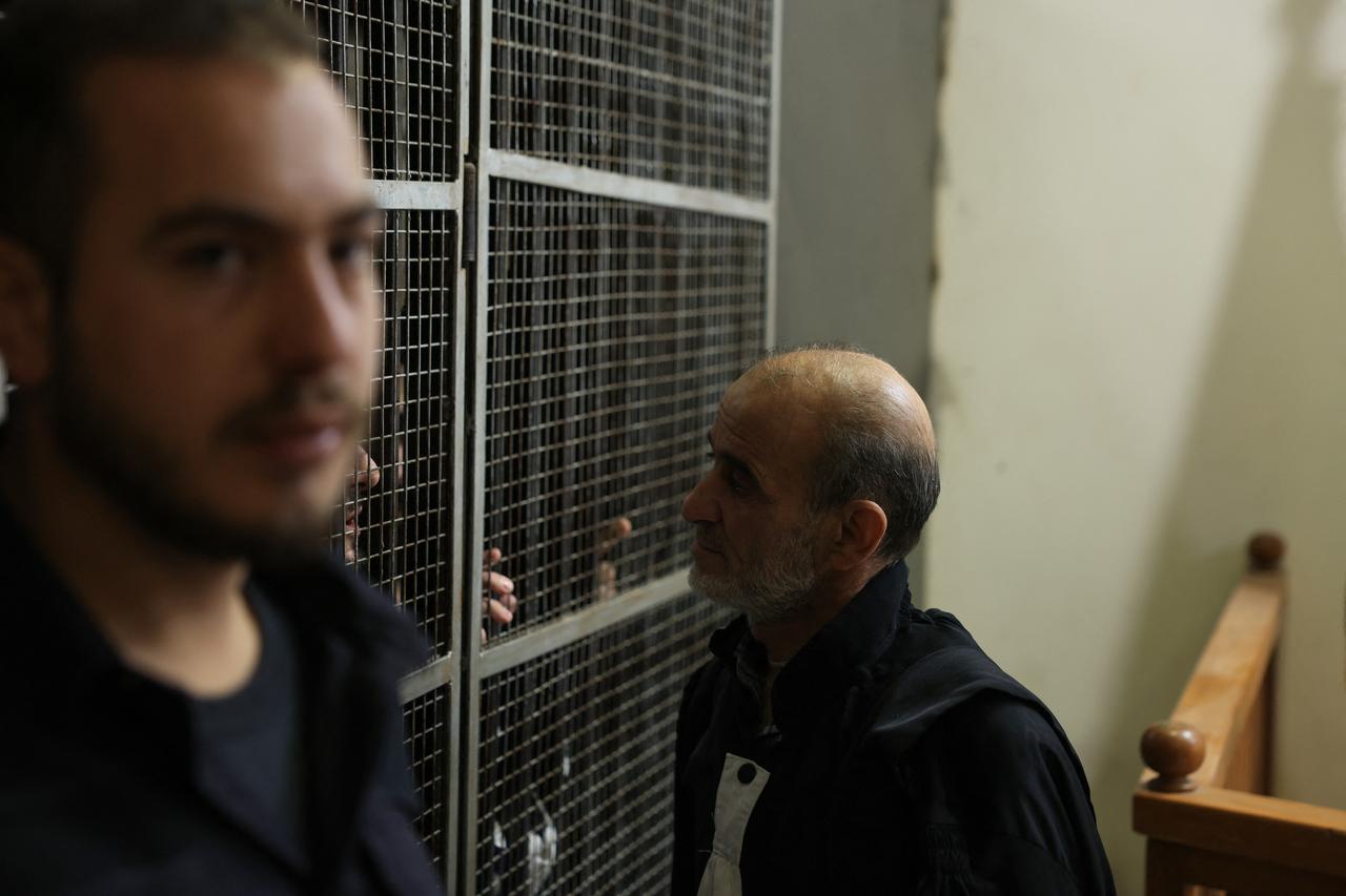 A man speaks with the accused during the first trial of more than a dozen suspects linked to massacres that left hundreds dead in Syria's Alawite coastal heartland earlier this year, at the Justice Palace in Aleppo, Syria on Nov. 18, 2025. (AFP Photo)