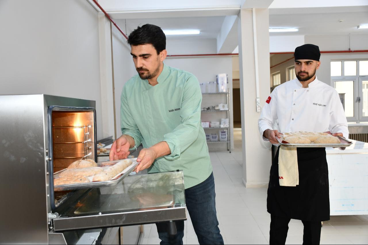 Lecturer Ilker Aksoy at Batman University places trays of dough into the oven as part of an effort to recreate ancient Mesopotamian honey-barley bread in Batman, Türkiye, Nov. 20, 2025. (AA Photo)