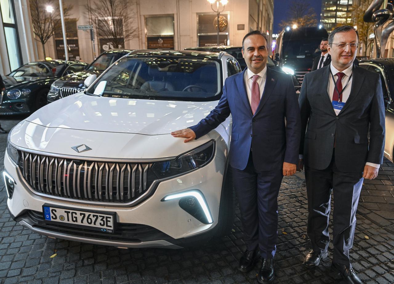 Turkish Industry and Technology Minister Mehmet Fatih Kacir (L) poses for a photo next to the Türkiye's domestic electric car TOGG as he leaves the hotel where the 2025 German-Turkish Automotive Summit was held in Berlin, Germany, November 20, 2025. (AA Photo)