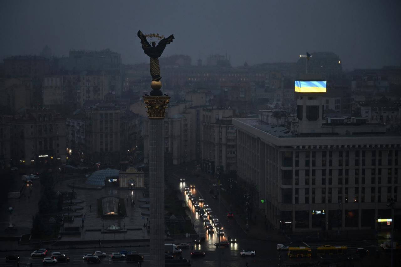Сars drive along Independence Square as a Ukrainian flag is displayed on a big screen during a power outage in Kyiv, November 20, 2025. (AFP Photo)
