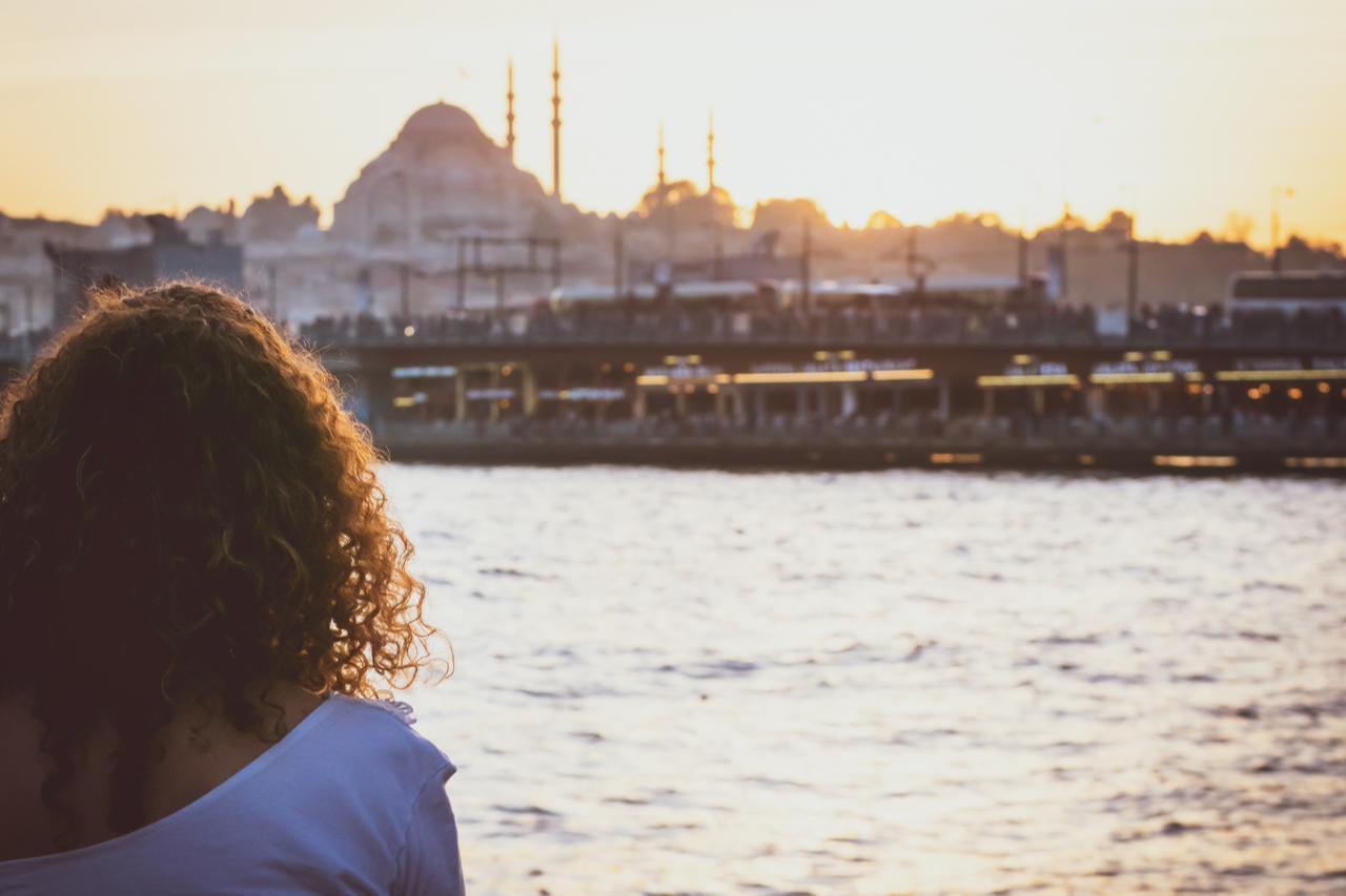 A young woman watches the Galata Bridge at sunset in Istanbul, Türkiye. (Adobe Stock Photo)