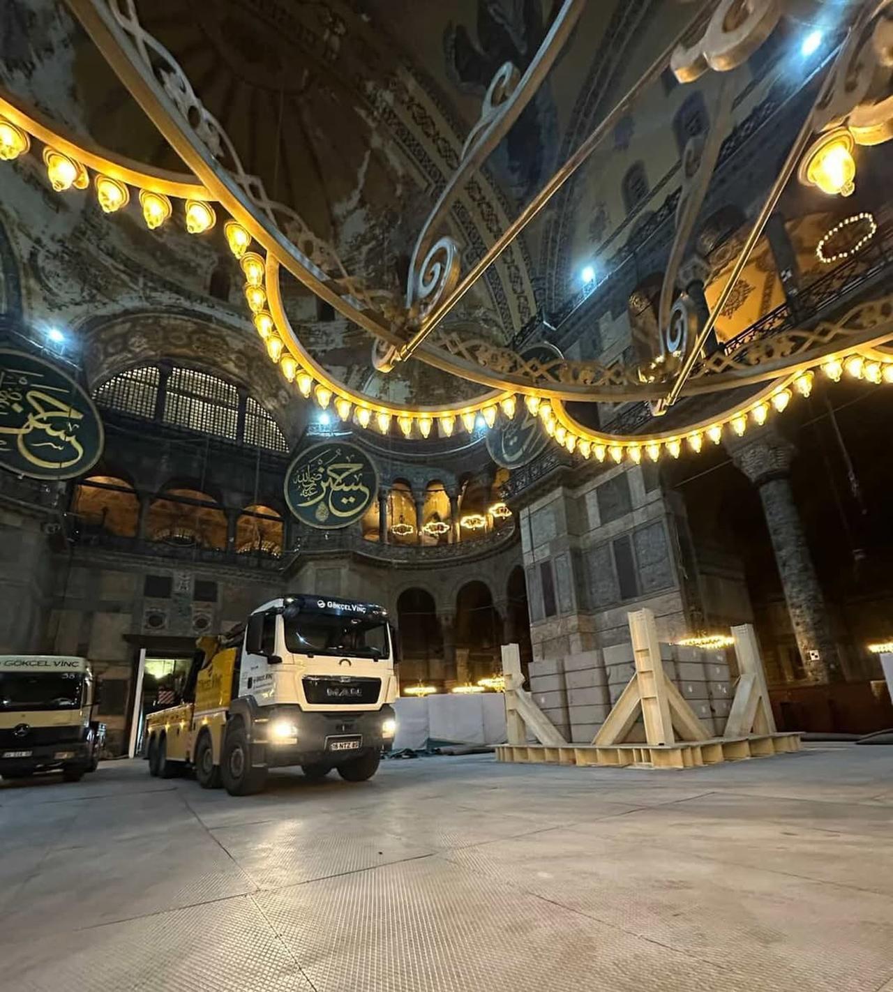 A medium-tonnage truck-mounted crane and a smaller utility truck are seen parked on protective floor panels inside Hagia Sophia during restoration works, beneath the historic dome and calligraphic medallions, Istanbul, Türkiye. (Photo via Instagram/@antiktarih)
