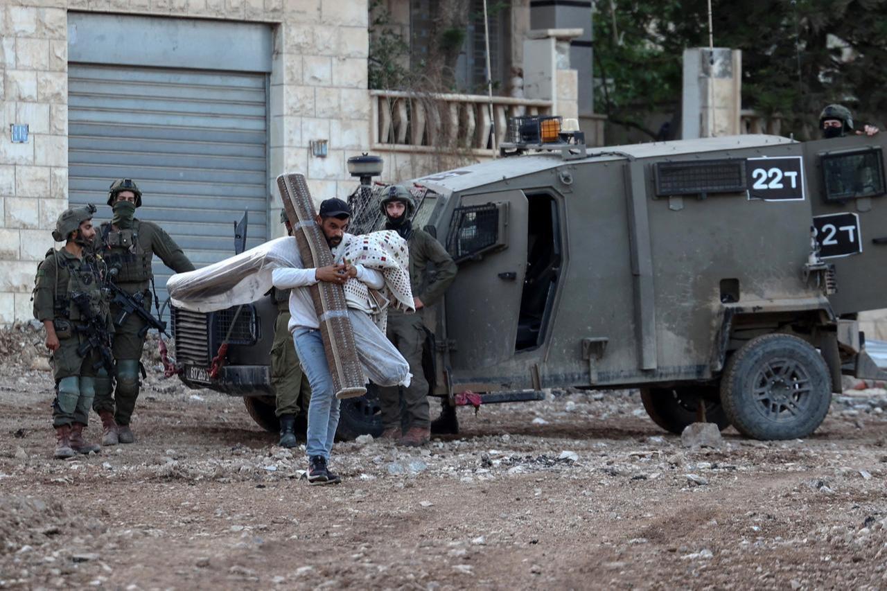 A Palestinian man carries his belongings as he evacuates his home during an Israeli army raid on the outskirts of the Jenin refugee camp in the occupied West Bank, November 27, 2025. (AFP Photo)