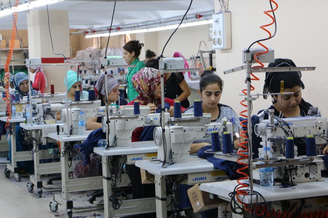 This image shows a garment production factory where female workers are using industrial sewing machines to produce clothing in Sanliurfa, Türkiye. (AA Photo)