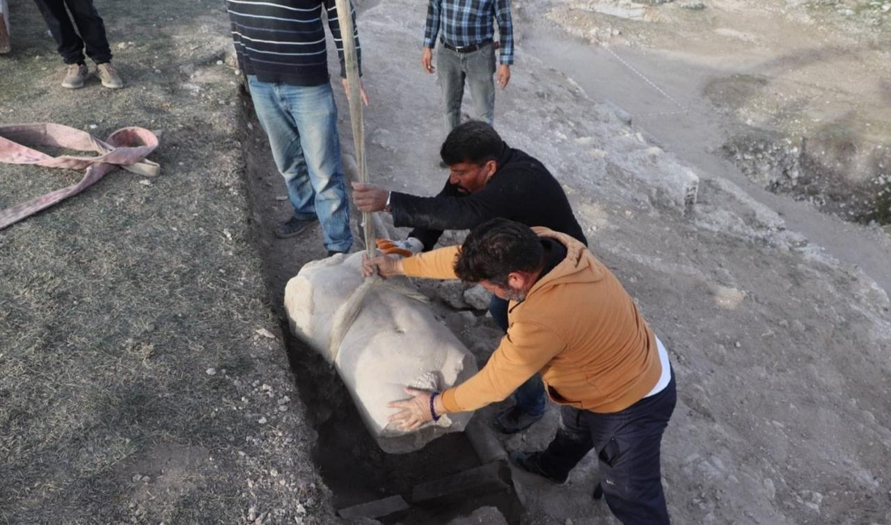 Workers carefully lift the newly uncovered Roman-era statue torso from the stadium wall during excavations at the ancient city of Blaundos in Usak, western Türkiye, Nov. 28, 2025. (Photo via Blaundos Excavations)