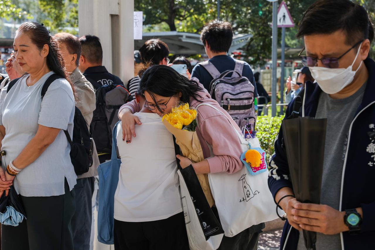 Mourners hug to comfort each other as they lay flowers to pay tribute to the deceased victims of the Wang Fuk Court apartment building fire, in Tai Po, Hong Kong, on Nov. 29, 2025. (AA Photo)