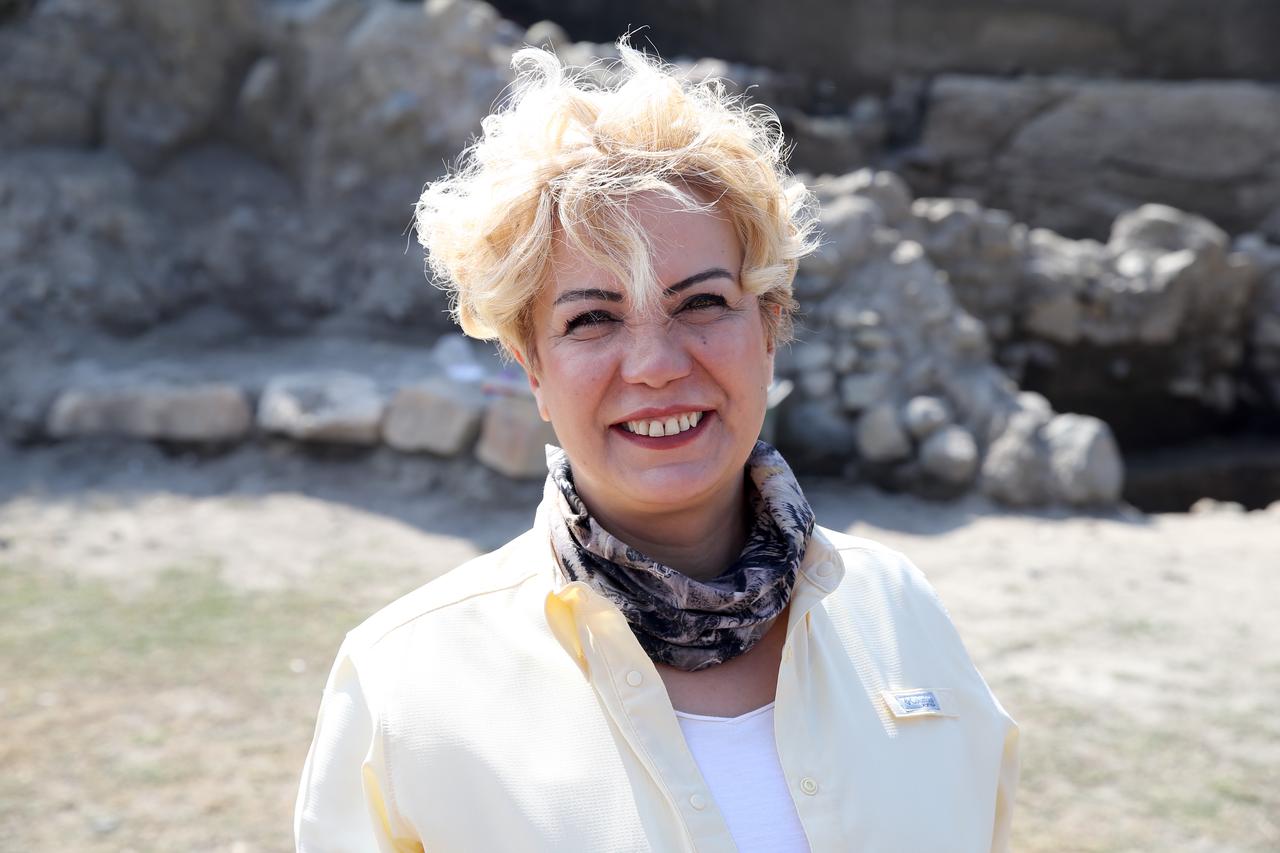 Archaeologist Gulsah Altunkaynak, excavation lead at Degirmenler Hoyuk, stands in front of newly revealed Early Bronze Age architectural remains, Erzurum, Türkiye, Nov. 2, 2025. (AA Photo)
